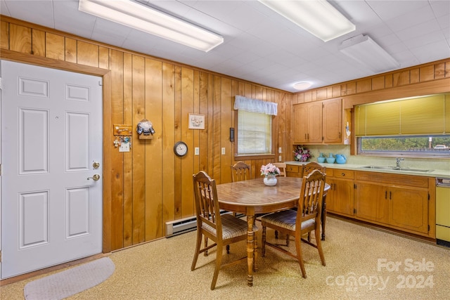 dining room with baseboard heating, wooden walls, and sink