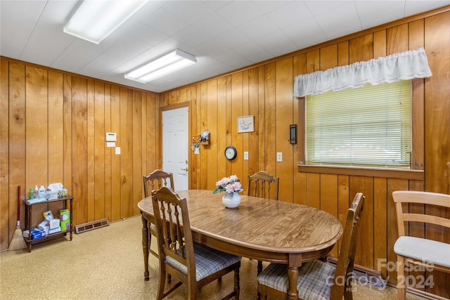 dining room featuring light colored carpet and wood walls