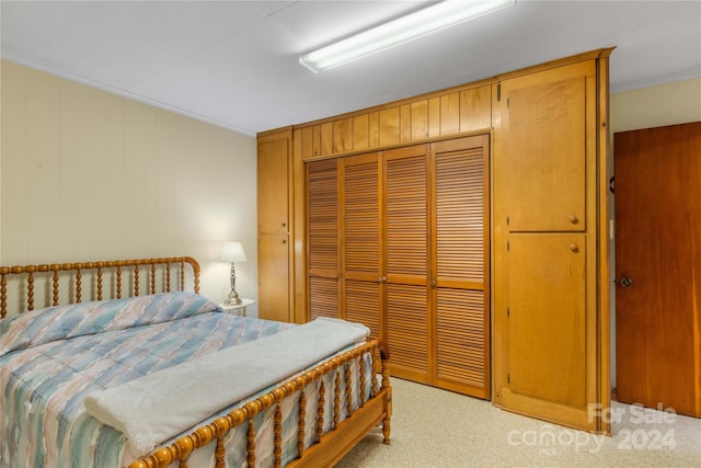 bedroom with light carpet, wooden walls, a closet, and crown molding