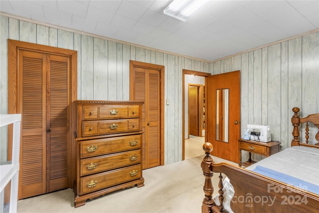 bedroom with wood walls, a closet, and light colored carpet