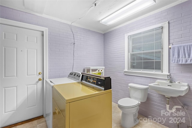 bathroom featuring toilet, washing machine and clothes dryer, sink, and tile patterned floors