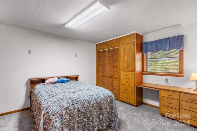 carpeted bedroom featuring a textured ceiling, a closet, crown molding, and built in desk