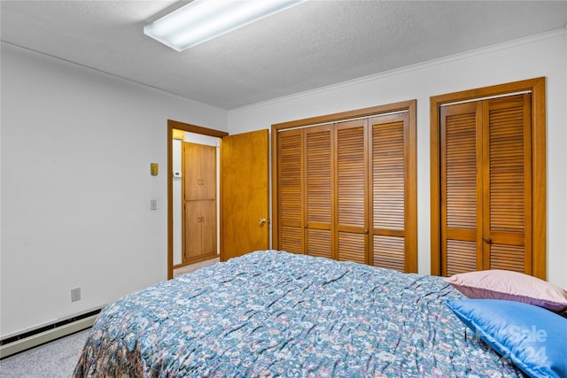 carpeted bedroom with two closets, a textured ceiling, and baseboard heating