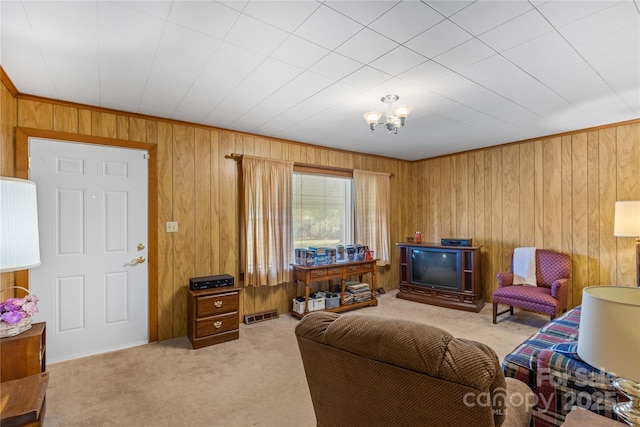 carpeted living room featuring a notable chandelier, ornamental molding, and wood walls