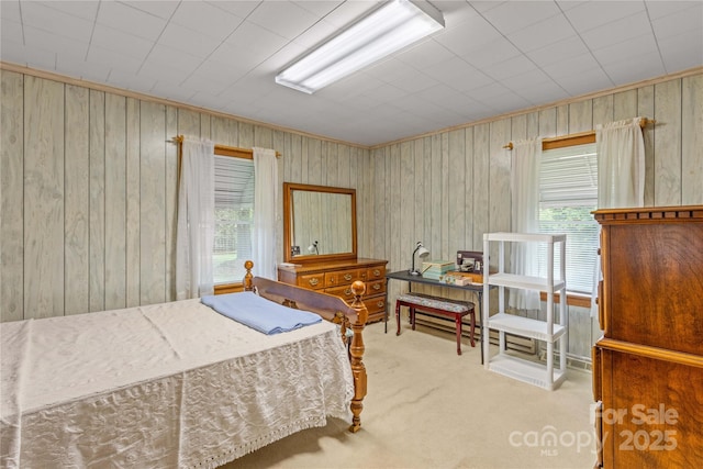 bedroom with multiple windows, light carpet, and wooden walls