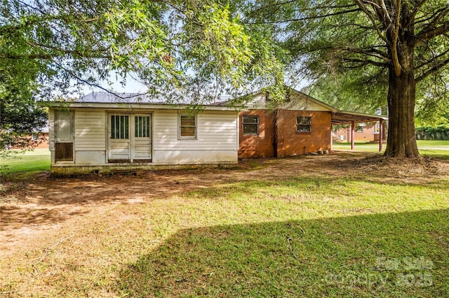 back of house featuring a carport and a lawn