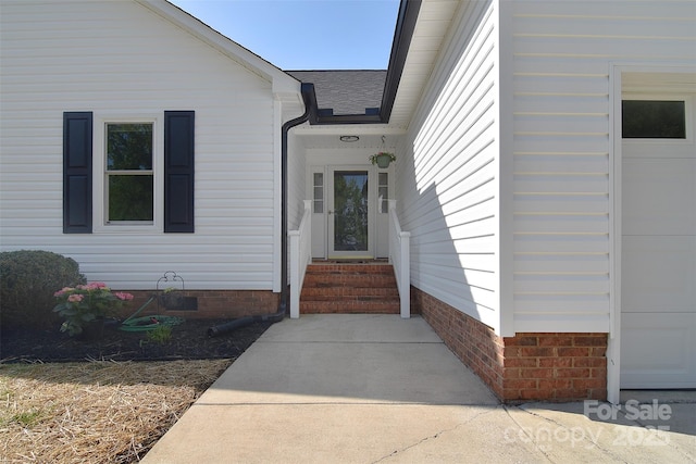 entrance to property with crawl space, a shingled roof, and a garage