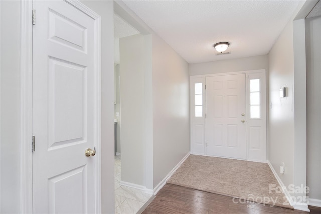 entryway with visible vents, baseboards, a textured ceiling, and wood finished floors