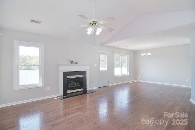 unfurnished living room featuring ceiling fan with notable chandelier, a glass covered fireplace, visible vents, wood finished floors, and lofted ceiling