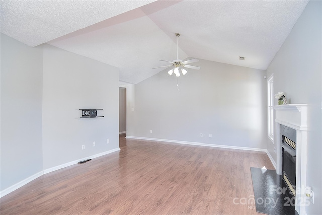 unfurnished living room featuring light wood-style flooring, ceiling fan, vaulted ceiling, and a fireplace