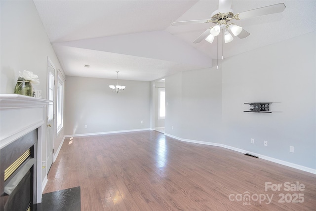 unfurnished living room with baseboards, ceiling fan with notable chandelier, wood finished floors, vaulted ceiling, and a fireplace with flush hearth