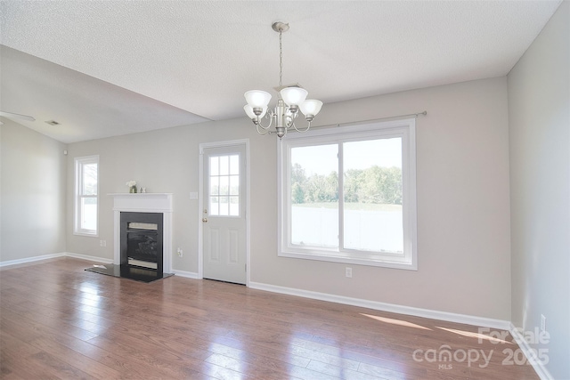 unfurnished living room featuring baseboards, hardwood / wood-style floors, and an inviting chandelier