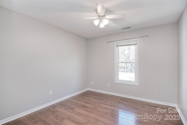 empty room featuring visible vents, baseboards, ceiling fan, and wood finished floors