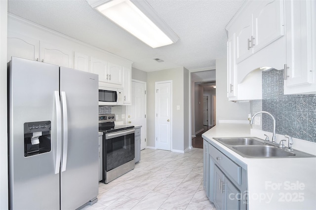 kitchen with tasteful backsplash, white cabinets, appliances with stainless steel finishes, marble finish floor, and a sink