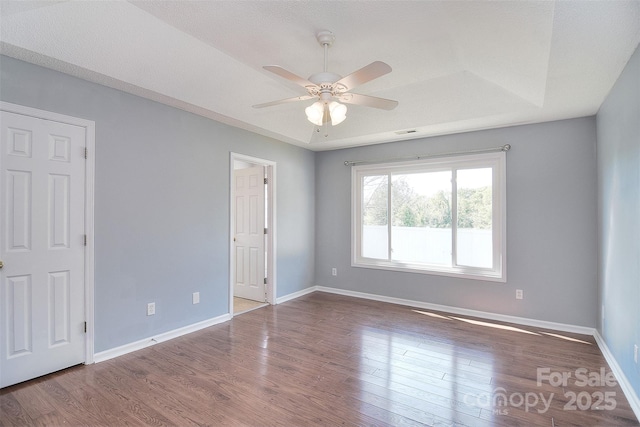 spare room featuring wood finished floors, baseboards, a ceiling fan, and visible vents