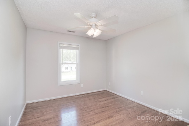 unfurnished room with visible vents, baseboards, a ceiling fan, a textured ceiling, and wood finished floors