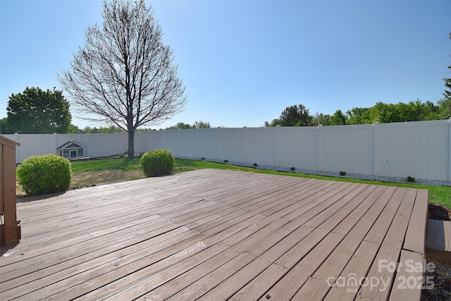 wooden deck featuring a fenced backyard and a lawn