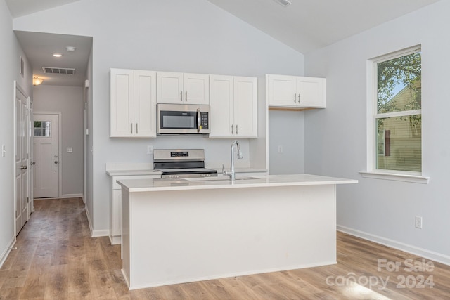 kitchen featuring vaulted ceiling, appliances with stainless steel finishes, white cabinetry, and a kitchen island with sink