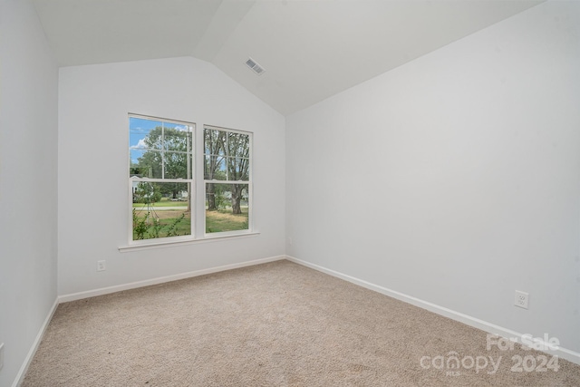 unfurnished room featuring lofted ceiling and carpet flooring