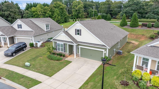 view of front of property with a garage, a front yard, and central air condition unit