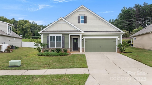 craftsman-style house featuring board and batten siding, a front lawn, fence, a garage, and driveway