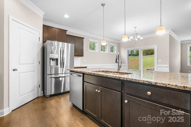 kitchen featuring stainless steel appliances, light stone countertops, sink, and decorative light fixtures