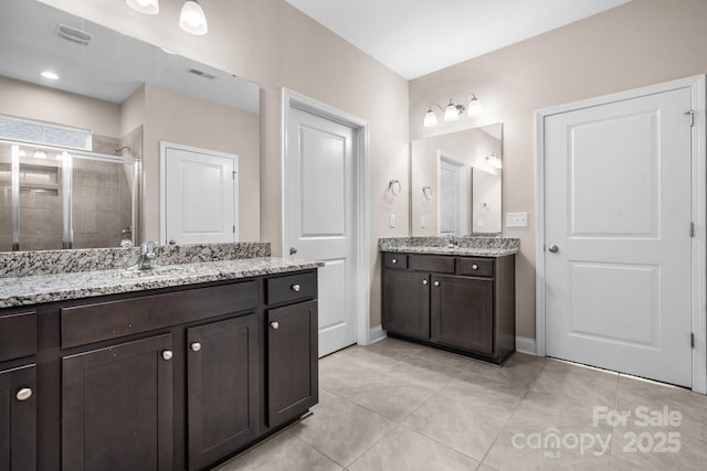 bathroom with a shower with door, vanity, and tile patterned flooring