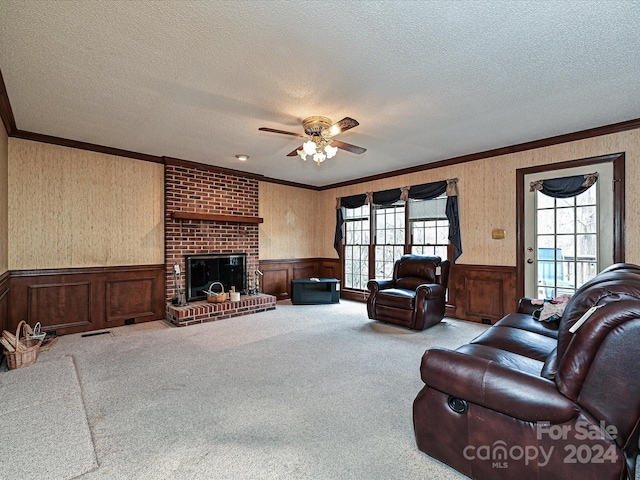 carpeted living room featuring ceiling fan, a fireplace, a textured ceiling, and ornamental molding