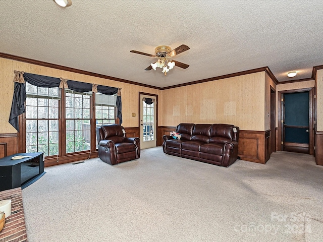 carpeted living room with ceiling fan, crown molding, a healthy amount of sunlight, and a textured ceiling