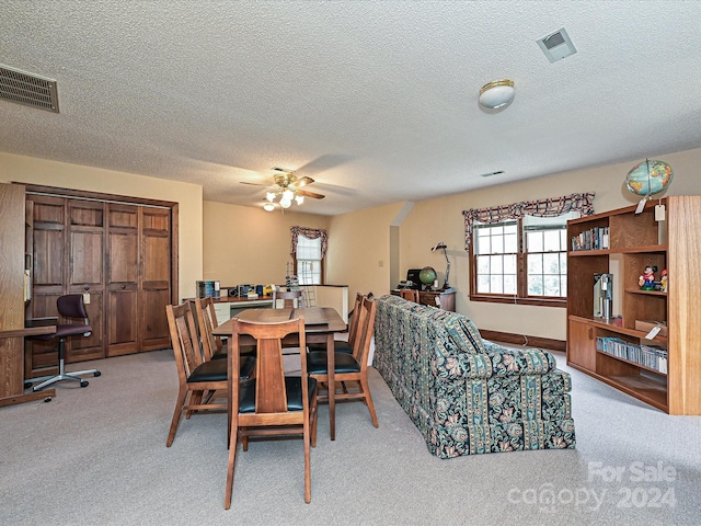 carpeted dining room featuring ceiling fan and a textured ceiling