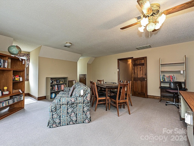 dining room with a textured ceiling, light colored carpet, and ceiling fan