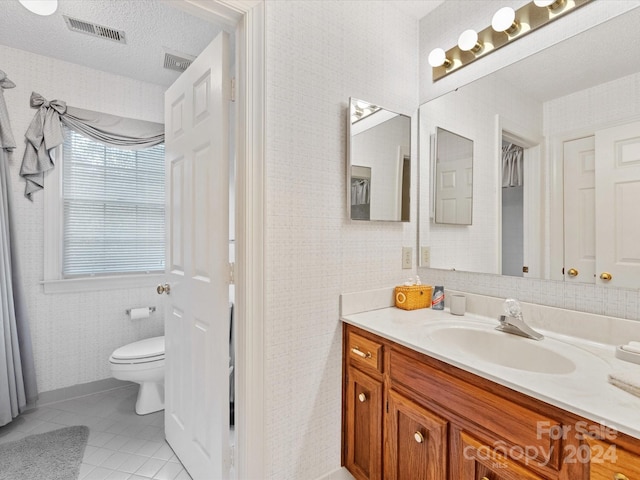 bathroom featuring tile patterned flooring, a textured ceiling, vanity, and toilet