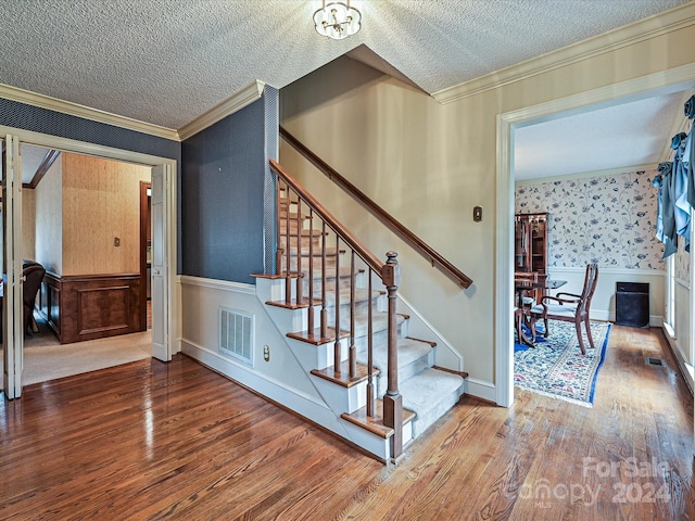 stairway featuring hardwood / wood-style flooring, a notable chandelier, crown molding, and a textured ceiling