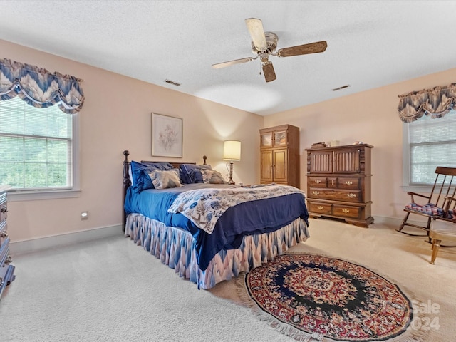 carpeted bedroom featuring ceiling fan and a textured ceiling