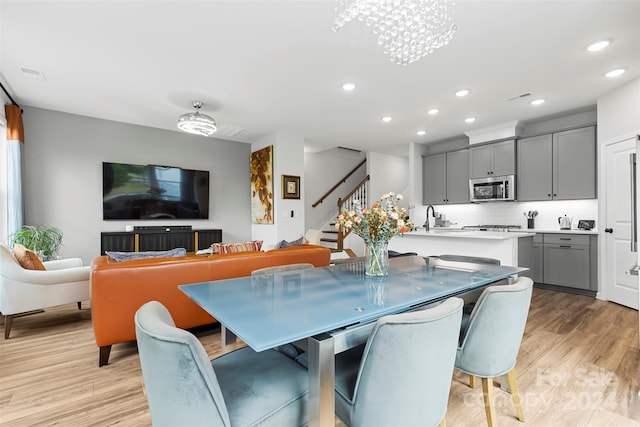 dining area featuring light hardwood / wood-style floors, sink, and a notable chandelier