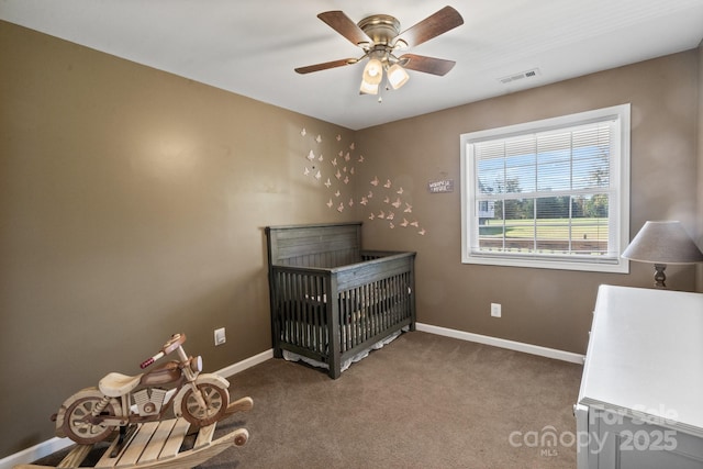 carpeted bedroom featuring ceiling fan and a crib