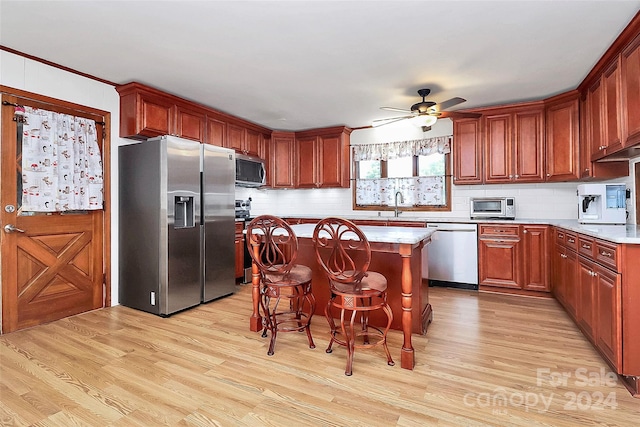 kitchen with tasteful backsplash, appliances with stainless steel finishes, light hardwood / wood-style flooring, and a center island