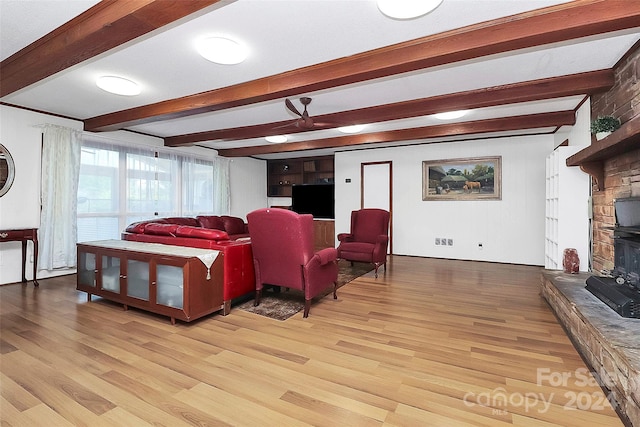 living room with a wood stove, beamed ceiling, and light hardwood / wood-style flooring