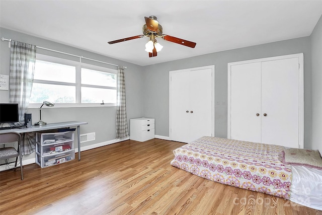 bedroom featuring ceiling fan, multiple closets, and light hardwood / wood-style floors