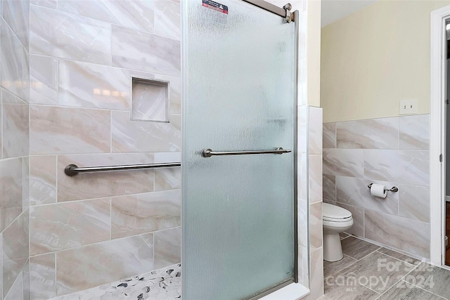 bathroom featuring tile walls, toilet, and an enclosed shower