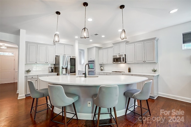 kitchen with pendant lighting, sink, a large island, stainless steel appliances, and a kitchen bar