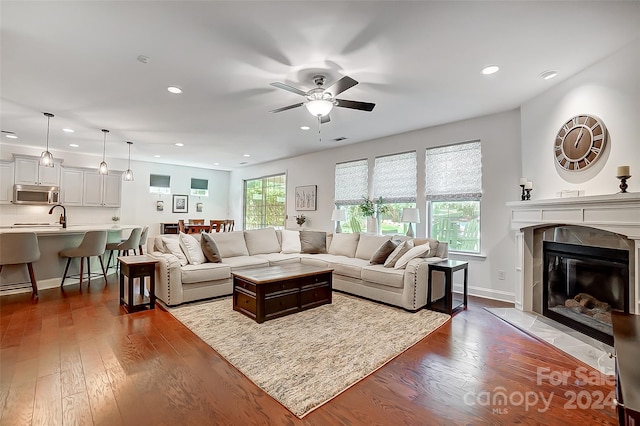 living room featuring ceiling fan, a tiled fireplace, and dark hardwood / wood-style flooring