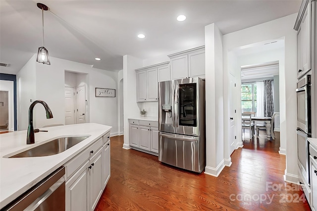 kitchen featuring decorative backsplash, dark hardwood / wood-style floors, sink, pendant lighting, and appliances with stainless steel finishes