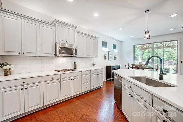 kitchen featuring sink, stainless steel appliances, backsplash, and dark hardwood / wood-style flooring