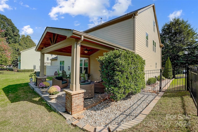 back of property with ceiling fan, an outdoor hangout area, a yard, and a patio area