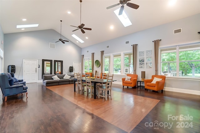 dining room with ceiling fan, a skylight, dark hardwood / wood-style flooring, and high vaulted ceiling