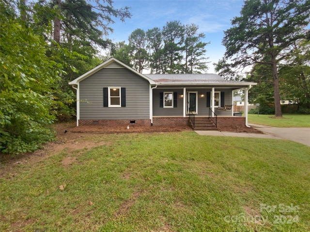 ranch-style house featuring covered porch and a front yard