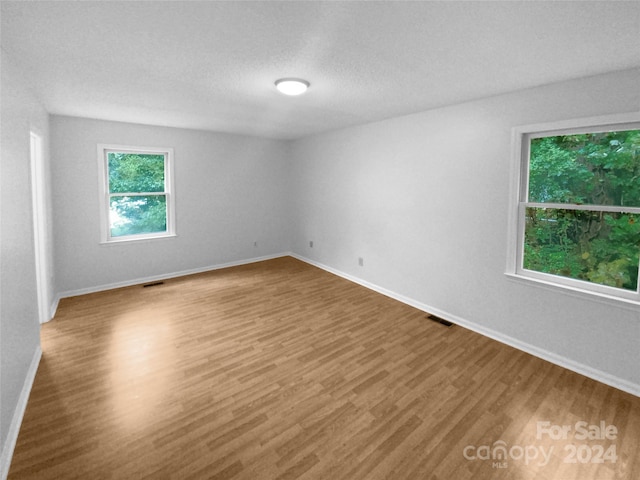 empty room with wood-type flooring and a textured ceiling