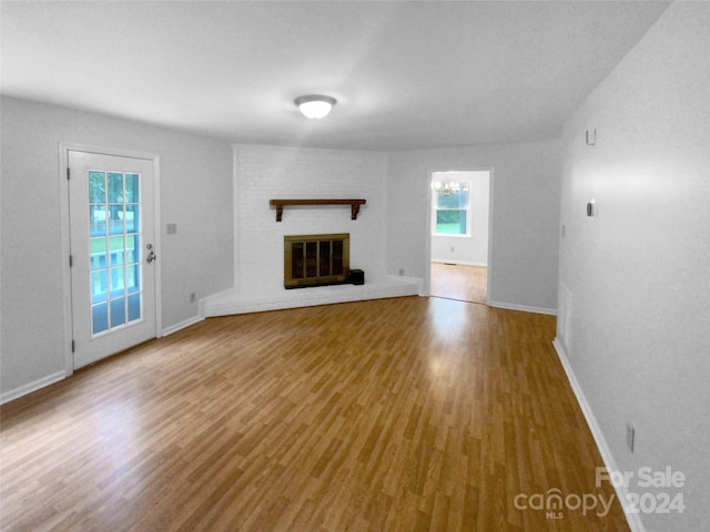 unfurnished living room with a brick fireplace and wood-type flooring