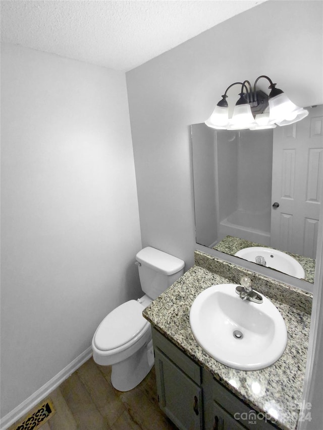 bathroom with hardwood / wood-style floors, a textured ceiling, vanity, and toilet